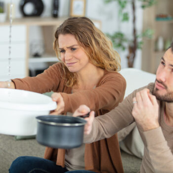 couple catching leaking water in a basin and saucepan