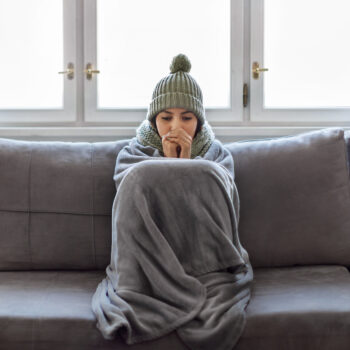Woman Covered With Blanket Freezing On Couch In Living Room