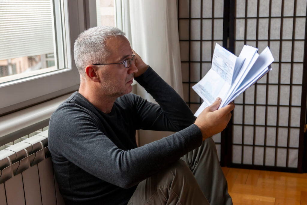 Stressed man looking at the high electricity bill because of the heat Expensive bills