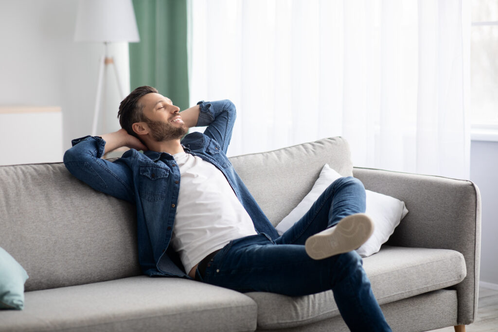 Happy bearded man relaxing on couch at home