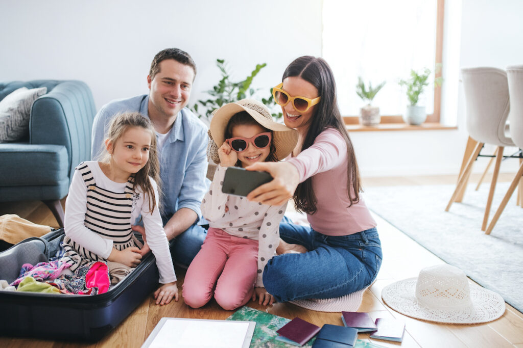 Parents with small daughters indoors at home, packing for summer holiday