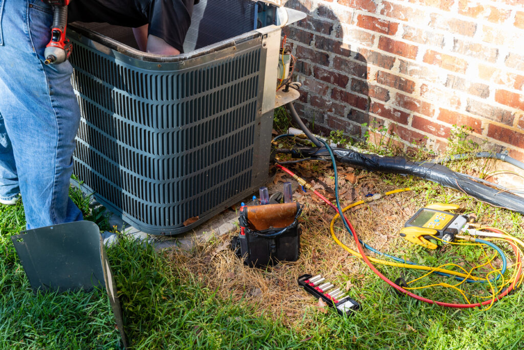 Air conditioner maintenance being performed on outdoor unit by technician